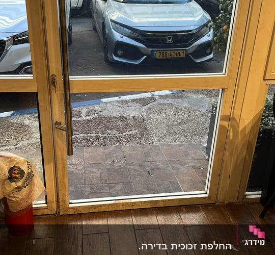 דלת זכוכית שקופה בכניסה לעסק עם ידית נירוסטה ארוכה